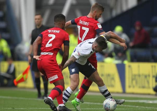 Sean Maguire takes the ball between Wigan's Nathan Byrne and Michael Jacobs at Deepdale