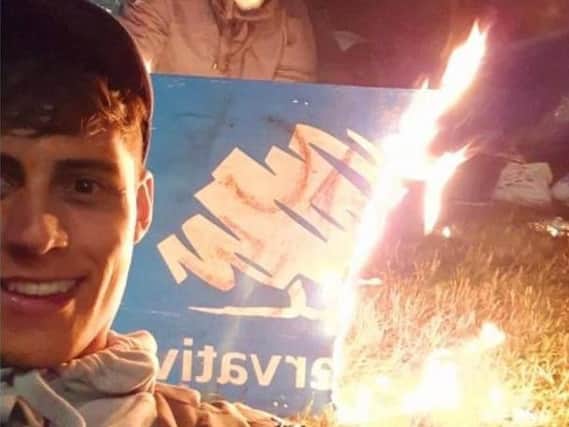 City councillor and Cabinet member Freddie Bailey pictured at a festival while others burn a Conservative party sign