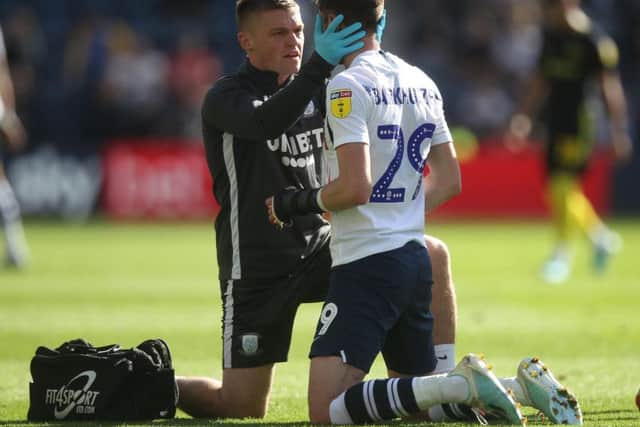 Tom Barkhuizen gets attention from PNE physio Matt Jackson after getting a bang in the face against Brentford