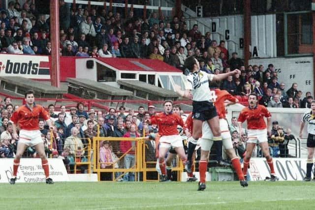 Preston defender Mike Flynn wins a header against Blackpool