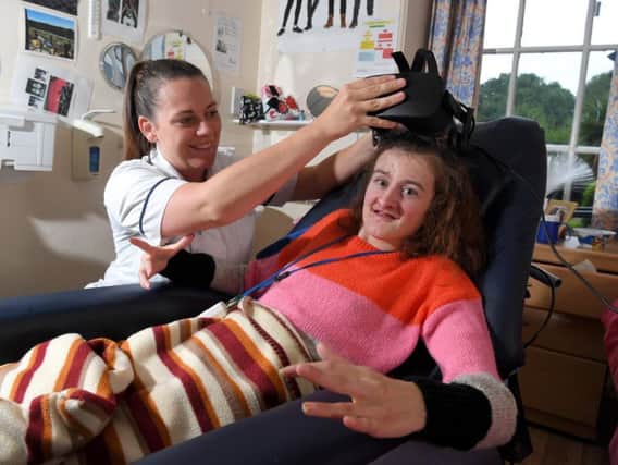 Physio Sinead Gallery helps Cuerden Hall resident Heather Barker try out a virtual reality headset. Photo by Neil Cross