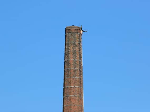 A figure, upside down with his legs in the air, at the top of the chimney