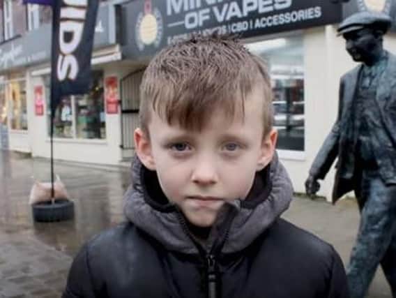 Lewis Anderson, eight, on film in front of the Leyland Motors man statue