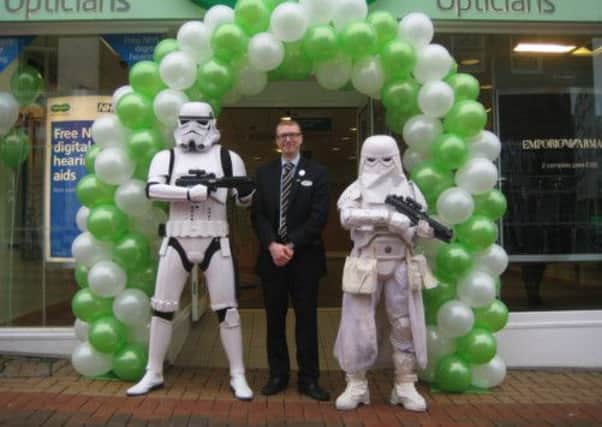GOING DOWN A STORM: Paul Slater, store manager at Specsavers in Chorley, celebrates a new look for the town centre opticians with two Storm Troopers