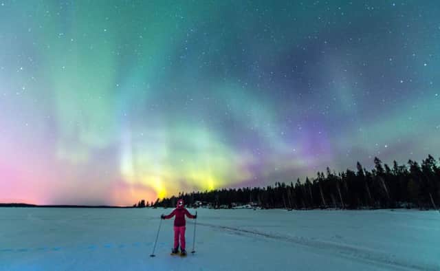 A girl snow shoeing over frozen Baltic Sea in Lulea, Sweden with Northern Lights in the background
