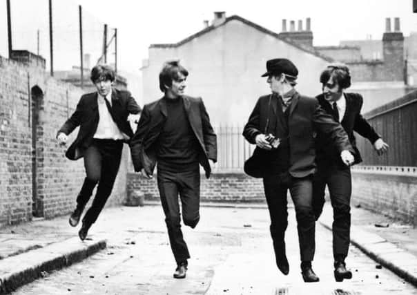 British rock group The Beatles run down an alley in a still from the film, 'A Hard Day's Night,' directed by Richard Lester, 1964.
