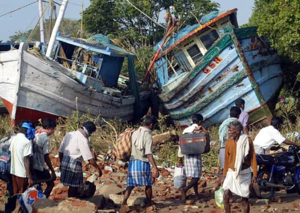 Villagers walk with their belongings past two boats that were washed ashore by tidal waves at Nagappattinam, in the southern Indian state of Tamil Nadu.