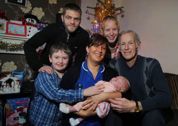 Nurse Angie Bose holds baby Carmel with neighbour Alan Widdows, right, pictured with, from left, Carmel's brother Vinnie, nine, dad Steven Poole and mum Rachel Booth.