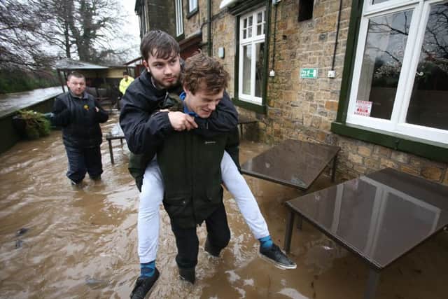 A man gives his friend a piggy back to escape rising flood water. The village of Ribchester on the River Ribble, Lancashire has burst its banks in the early hours of this morning Saturday 26 December. A Severe flood warning has been issued with a danger to life. Heavy rain fell over Christmas night and forecasters have warned it will continue in Lancashire for most of the day. Rivers in the are are expected to peak around mid-day.