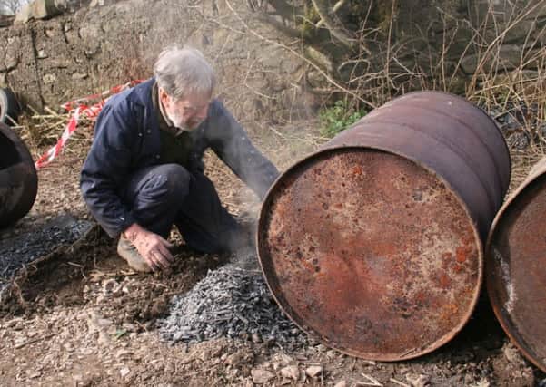 Brian Crawley empties biochar from a drum.