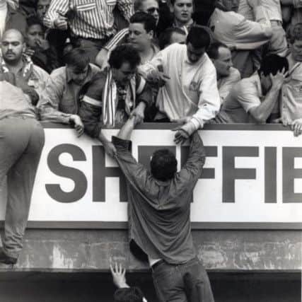 Paul Walmsley at Hillsborough (top, above man in white shirt) standing with his friend John Barlow (to Paul's left in sunglasses) in the stand just after being pulled up to safety.
Their friend Nigel Newman is out of shot.
