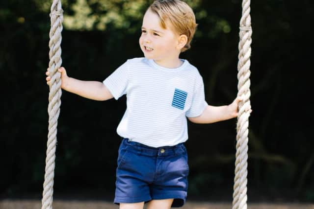 Prince George, who celebrates his third birthday today, standing on a swing.
