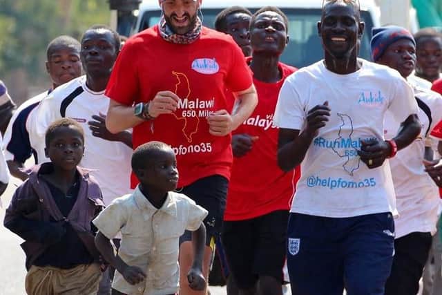 Brendan Rendall running with villagers in Malawi