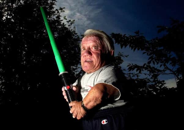 R2D2 actor Kenny Baker poses with a light sabre for the 30th anniversary of the release of Star Wars: A New Hope