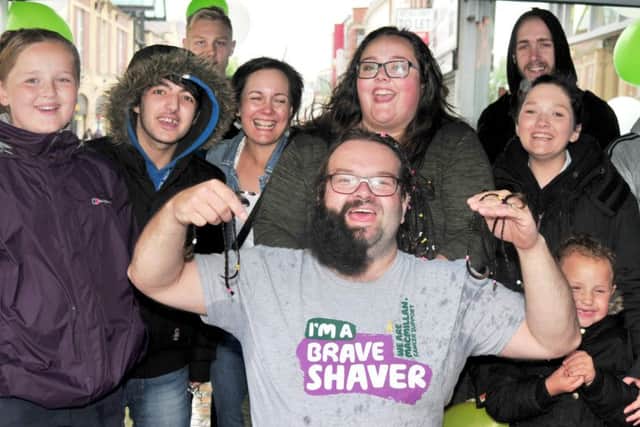 Photo: David Hurst Gavin Howard has his plaits and beard cut and shaved in small parts by passers by on Friargate in aid of Macmillan Cancer, pictured with his family and supporters