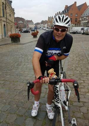 John Wright on his charity cycle from London to Ghent in Belgium, with his lucky mascot, Rosemere Ted, having reached the top of a steep cobbled climb in France