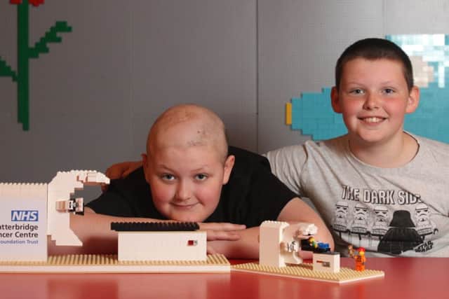 LEGOLAND Discovery Centre Manchester has built a LEGO model radiography machine which will be donated to help staff explain treatment to children at The Clatterbridge Cancer Centre.  Pictured Reece Holt, a young patient who was treated with radiotherapy for a brain tumour at The Clatterbridge Cancer Centre, his brother Callum, and Master Model Builder, Alex Bidolak, from LEGOLAND Discovery Centre Manchester.