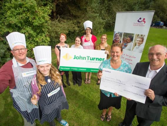 John Turner Construction site manager, Brian Yates with his daughter Alex; TLC group members; Sharon Stephenson-Baird presenting the cheque to Eric Kent from The National Autistic Society