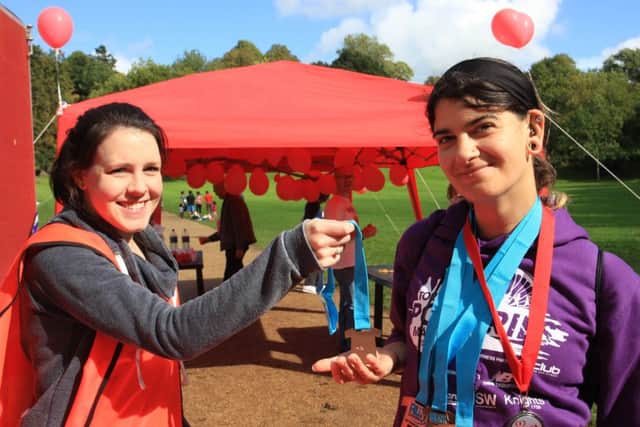 Gina Briggs receiving her fourth medal of the day from a Heartbeat volunteer after completing the 10k, 5k, 2k and 1k runs on the day.
