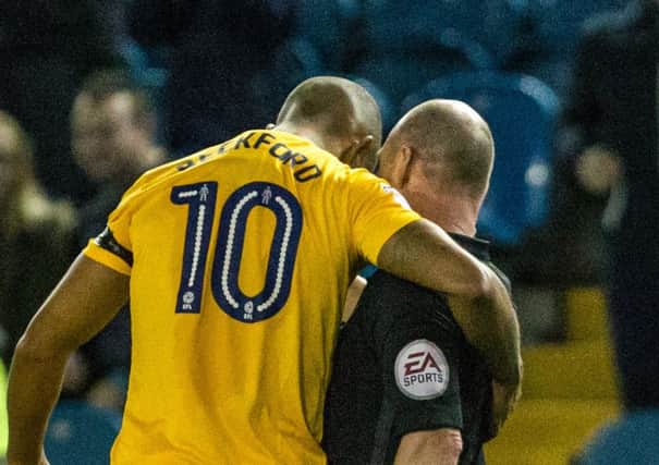 Jermaine Beckford puts his arm around referee Scott Duncan after his red card