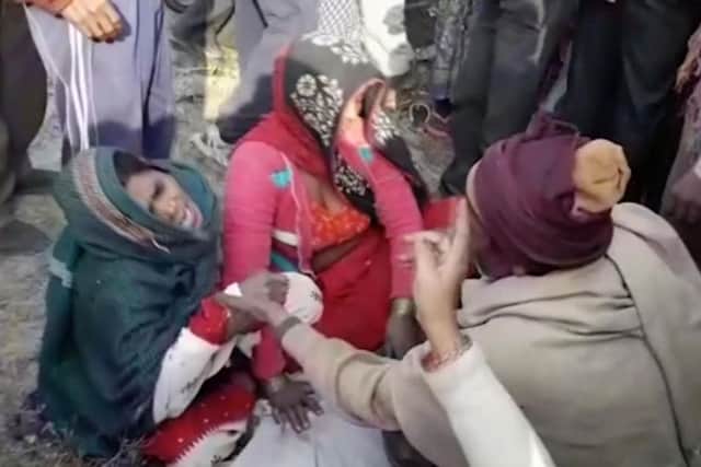 In this image from video, relatives cry over the covered body of a child after a traffic accident