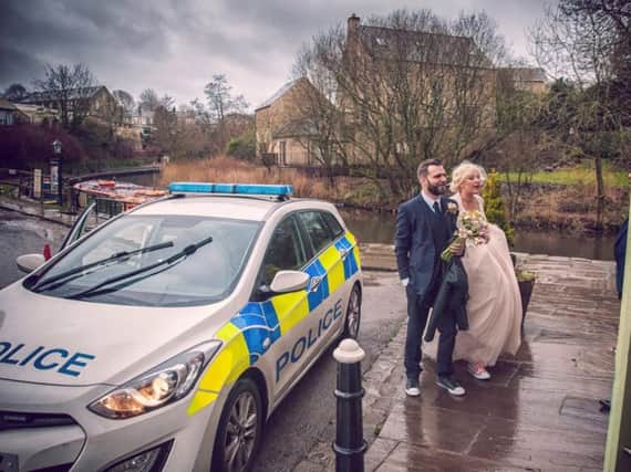 Georgia and Emmott Garnett arrive at their reception in a police patrol car after their vintage Rover was involved in a crash on the way there.