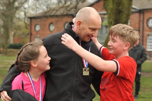 Photo Neil Cross
Darren Nicholls suffered a cardiac arrest whilst training for a 5K run in Astley Park, Chorley, and was saved by race volunteers using a defibrillator
Darren's son Brandon presents his dad with his own medal, watched by daughter Louise