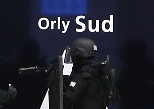An elite police officer enters the Orly airport departure terminal, south of Paris, Saturday, March, 18, 2017. A man was shot to death Saturday after trying to seize the weapon of a soldier guarding Paris' Orly Airport, prompting a partial evacuation of the terminal, police said. (AP Photo/Kamil Zihnioglu)