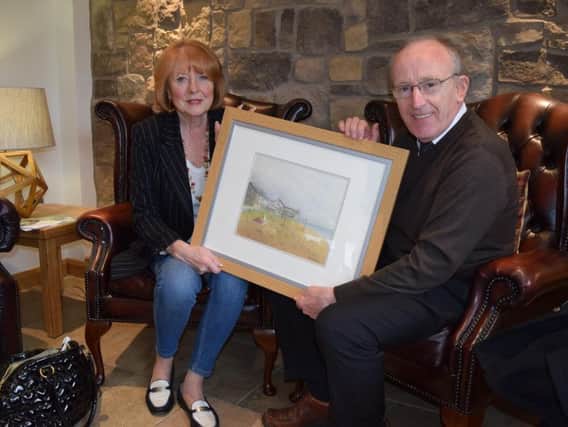 Christine Montgomery and artist Edwin Williams at The Mill, with the painting he donated to St Catherines Hospice