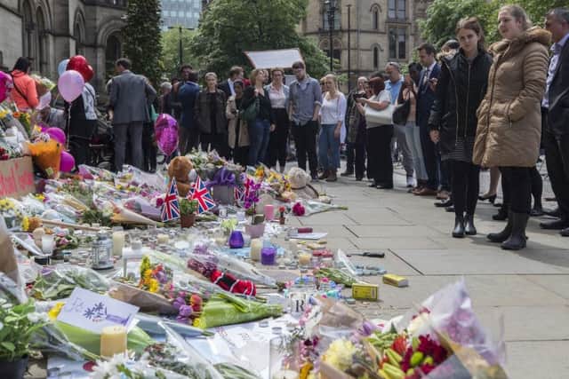 People look at flowers outside the Town Hall in Albert Square, Manchester after a suicide bomber killed 22 people leaving a pop concert at the Manchester Arena on Monday night. PRESS ASSOCIATION Photo. Picture date: Wednesday May 24, 2017. The attack killed 22 people, including children, and injured dozens more in the worst terrorist incident to hit Britain since the July 7 atrocities. See PA story POLICE Explosion. Photo credit should read: Peter Byrnel/PA Wire