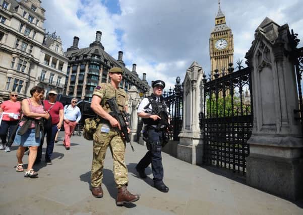 A member of the army joins police officers outside the Houses of Parliament in London
