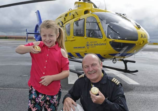 10-year-old Amber Hardman has helped raise Â£1,200 for NWAS by selling cakes.  She is pictured with pilot Captain Neil Airey.