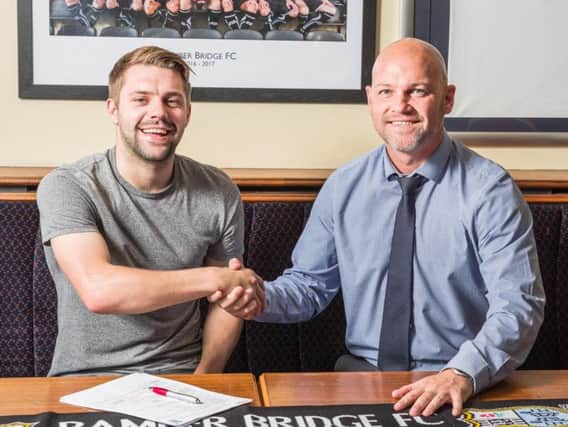 Alistair Waddecar shakes hands with manager Neil Reynolds after agreeing a new two-year contract with the club