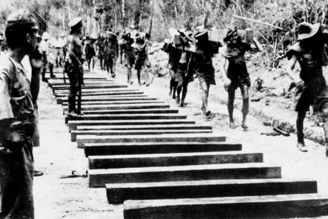 Prisoners of war carrying sleepers for the Burma-Thailand Railway about 40km south of Thanbyuzayat, in Burma, circa 1943