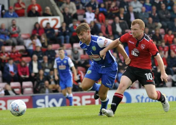 One of Morecambe's summer signings Adam Campbell battles with Lancaster City's Ryan Winder.