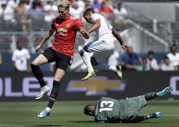 Manchester United's Scott McTominay, left, and Real Madrid's Fabio Coentrao jump over Real Madrid goalie Francisco Casilla. AP Photo/Ben Margot