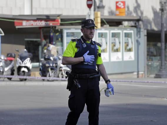 A police officer cordons off a street in Barcelona after a van crashed on a pavement in the city's historic Las Ramblas district, injuring several people (AP)