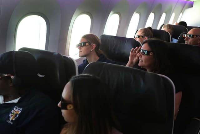 Nicola James, 49, (right centre) with her twin 18 year old daughters Holly (left centre) and Grace (left rear) watch the start of the solar eclipse while flying over the United States on board Virgin Atlantic Boeing 787 Dreamliner flight check VS5 from London's Heathrow airport to Miami.