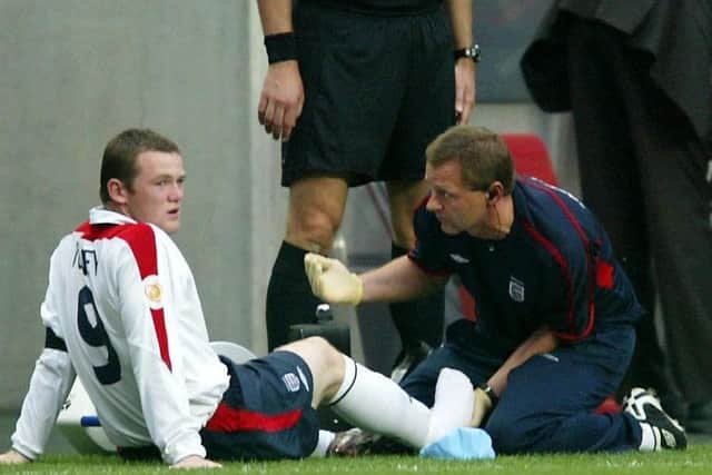 Rooney (left) receives treatment after an injury against Portugal during the Euro 2004 quarter-final