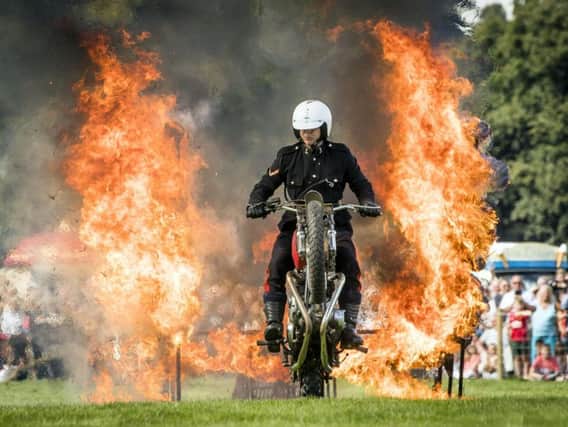 A White Helmets motorcyclist driving through a ring of fire