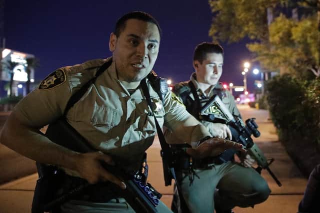 Police officers advise people to take cover near the scene of a shooting near the Mandalay Bay resort and casino on the Las Vegas Strip (AP Photo/John Locher)