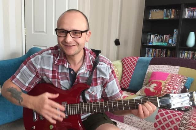 Phil Woodford playing the guitar before his stroke. He is determined to play again one day