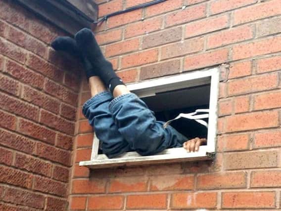 A man who is being questioned about a suspected break-in after police found him stuck in a takeaway extractor fan unit