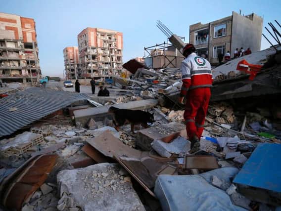 In this photo provided by the Iranian Students News Agency, ISNA, a rescue worker searches debris for survivors with his sniffing dog after an earthquake at the city of Sarpol-e-Zahab in western Iran.