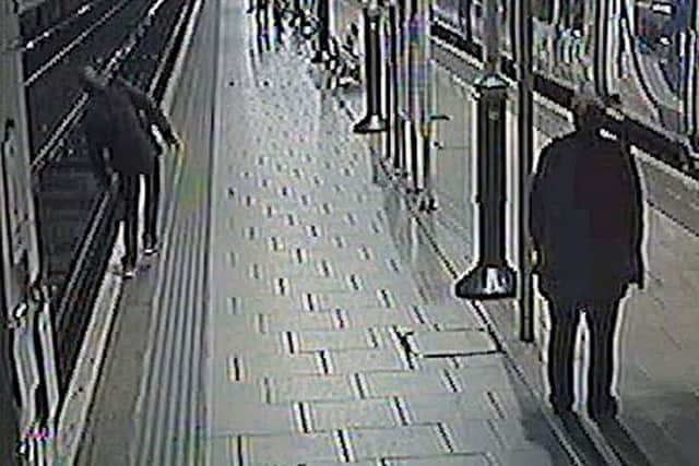 A man (left) about to fall on to the tracks at a railway station