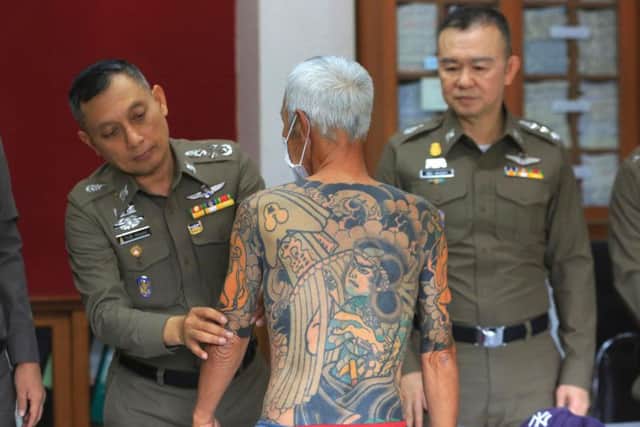Japanese gang member Shigeharu Shirai displays his tattoos at a police station