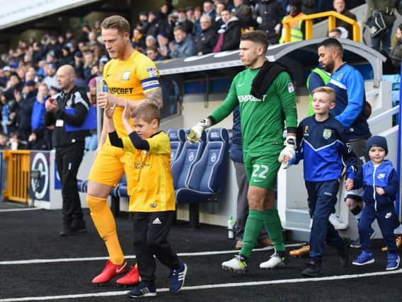 Tom Clarke leads Preston out at Millwall.
