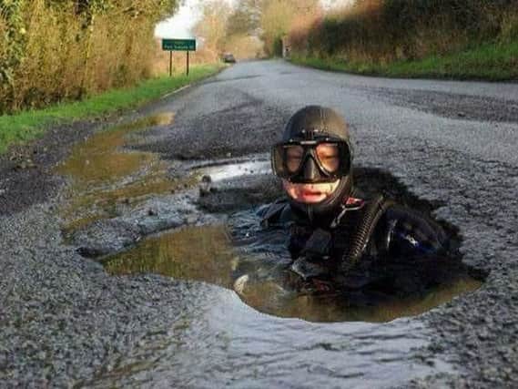 In one picture a scuba diver pops up from one water-logged hole in the road.