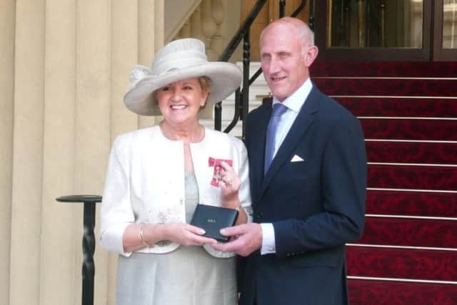 Norah Hoyles, accompanied by her husband, Henry, displays her MBE after being presented with the award by the Queen at Buckingham Palace.