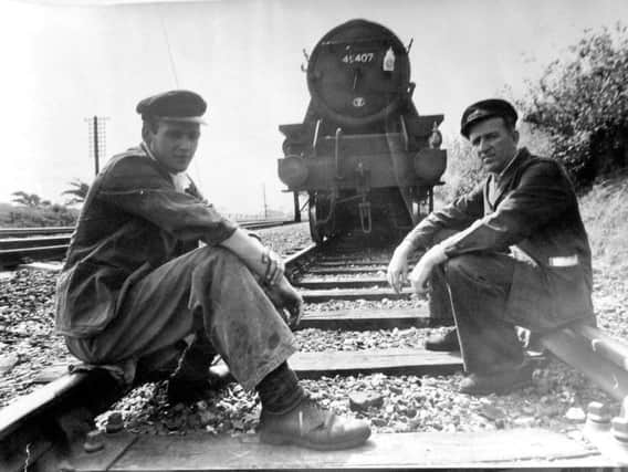 Fireman John Fletcher, left, and driver Clifford Nelson relaxing on the rails outside Morecambe during a delay in services
